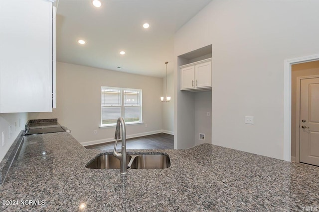 kitchen with sink, dark stone countertops, white cabinets, hanging light fixtures, and range