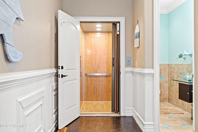 interior space featuring dark tile flooring, elevator, and crown molding