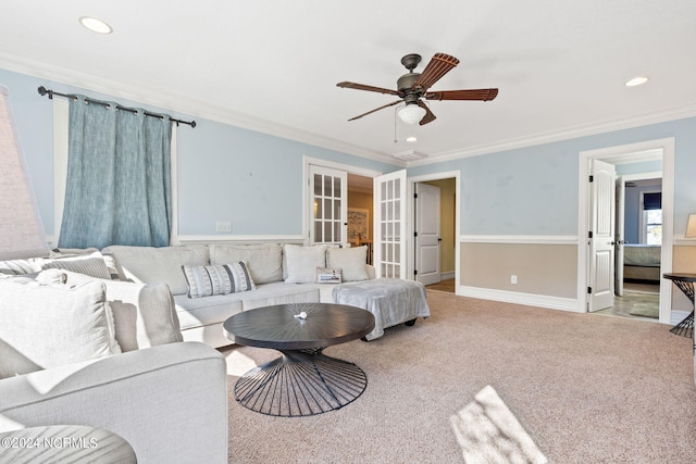 living room featuring ceiling fan, french doors, ornamental molding, and light carpet