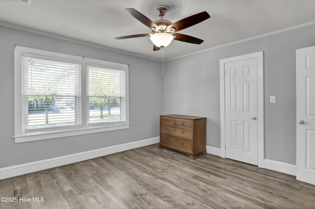 unfurnished bedroom with crown molding, baseboards, ceiling fan, and wood finished floors