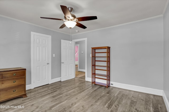 unfurnished bedroom featuring ceiling fan, baseboards, ornamental molding, and wood finished floors