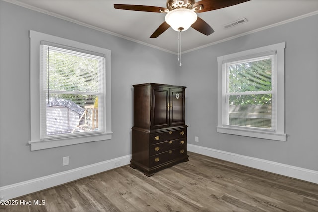 spare room featuring baseboards, visible vents, light wood-type flooring, and crown molding