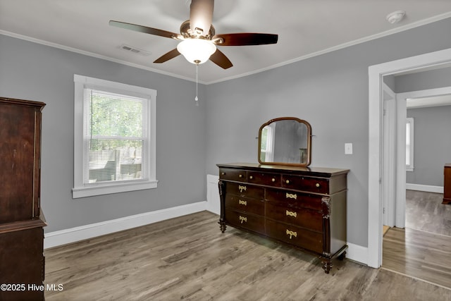 bedroom featuring wood finished floors, baseboards, ornamental molding, and visible vents