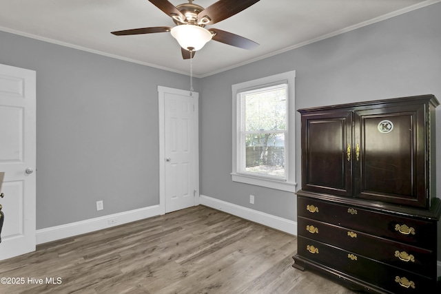 unfurnished bedroom with crown molding, light wood finished floors, and baseboards