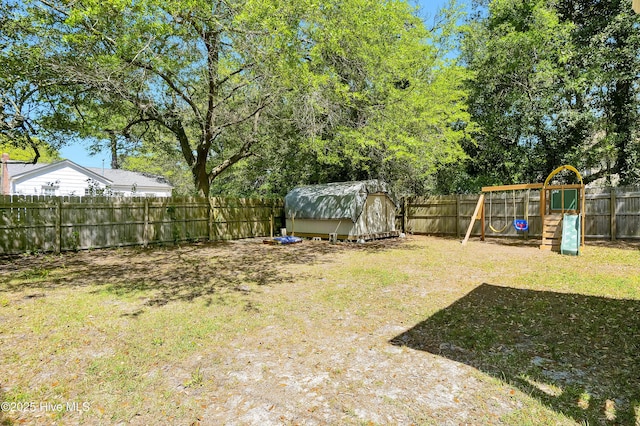 view of yard with a shed, an outbuilding, a fenced backyard, and a playground