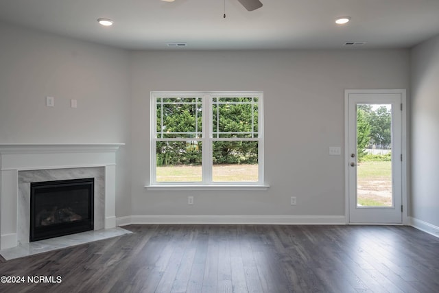 unfurnished living room with ceiling fan, a fireplace, and dark wood-type flooring