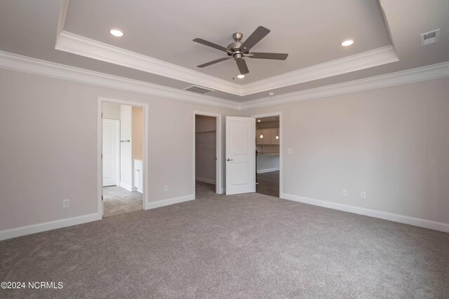 unfurnished room with a tray ceiling, crown molding, and carpet flooring