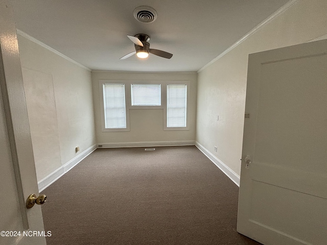 unfurnished room with ceiling fan, dark carpet, and ornamental molding