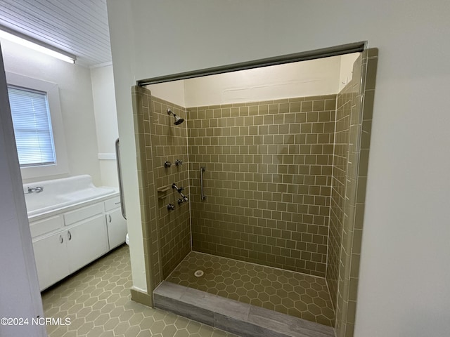 bathroom with tile floors, tiled shower, and vanity