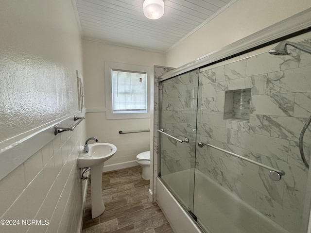 full bathroom with combined bath / shower with glass door, crown molding, toilet, wood-type flooring, and tile walls