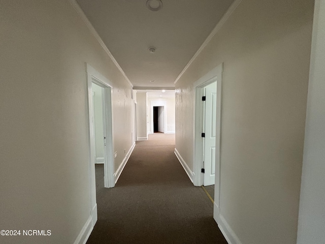 corridor featuring ornamental molding and dark colored carpet