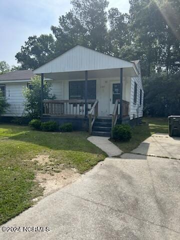 bungalow-style house with a front yard and covered porch