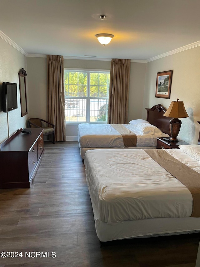 bedroom with dark hardwood / wood-style flooring and ornamental molding