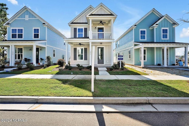 view of front of property with ceiling fan, a balcony, and a front yard