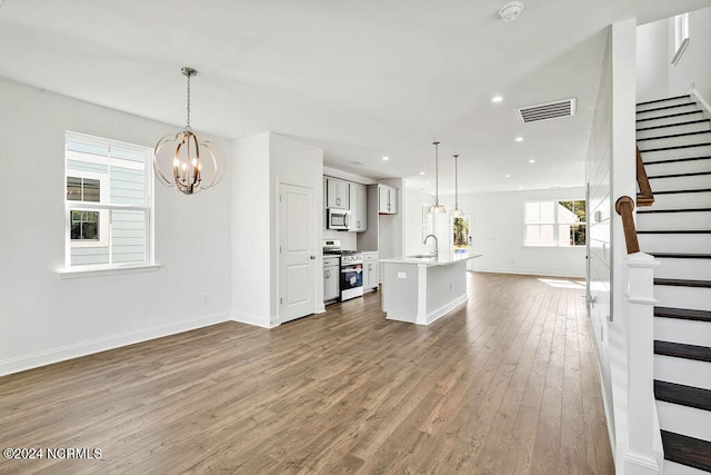 unfurnished living room featuring wood-type flooring, a notable chandelier, and sink