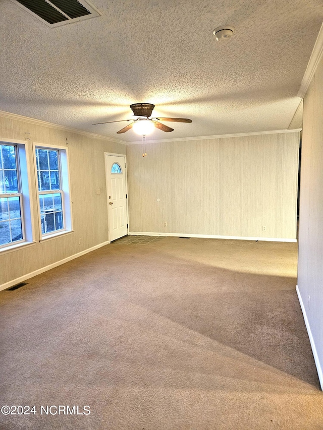 carpeted spare room with ornamental molding, ceiling fan, and a textured ceiling