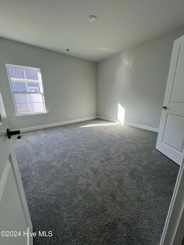 unfurnished room featuring dark colored carpet