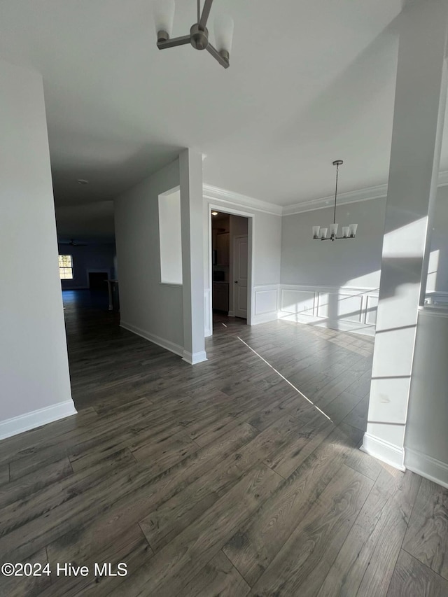 unfurnished room featuring ceiling fan with notable chandelier, dark hardwood / wood-style flooring, and crown molding