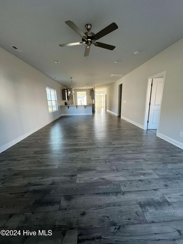 unfurnished living room with dark hardwood / wood-style flooring and ceiling fan