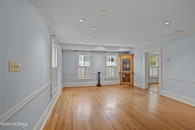 spare room featuring a wealth of natural light, crown molding, and light hardwood / wood-style floors