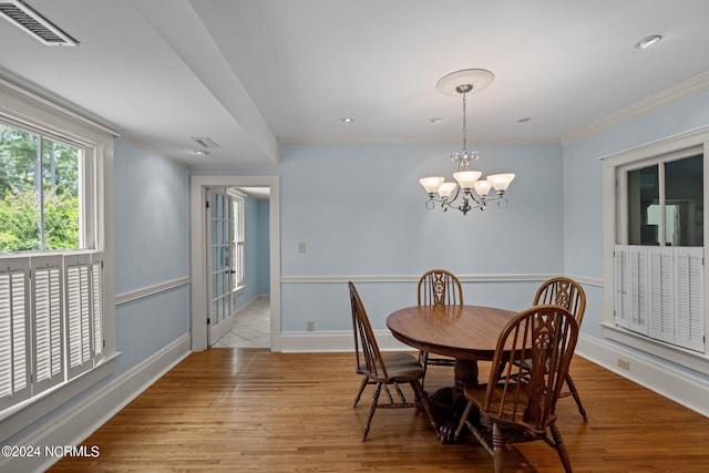 dining space with ornamental molding, a notable chandelier, and light hardwood / wood-style floors