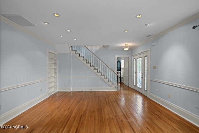 unfurnished room with ornamental molding, built in shelves, and wood-type flooring