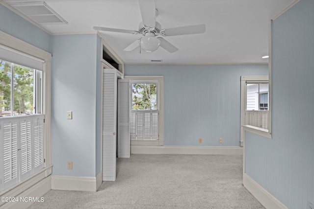 unfurnished bedroom with multiple windows, ornamental molding, light colored carpet, and ceiling fan