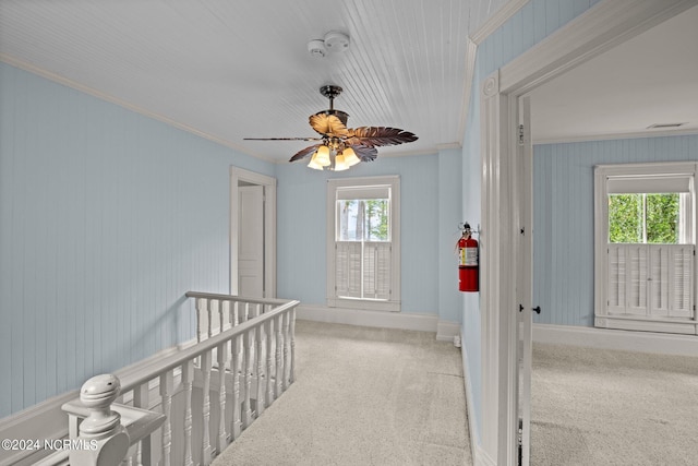 corridor featuring light carpet, crown molding, and a wealth of natural light