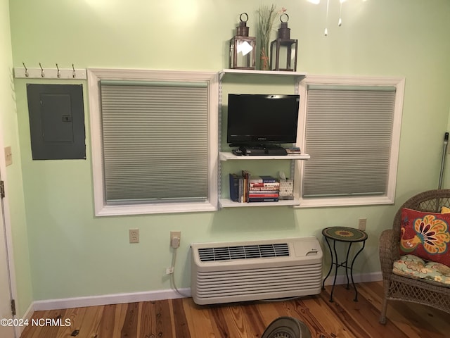 interior space featuring electric panel, a wall mounted air conditioner, and wood-type flooring