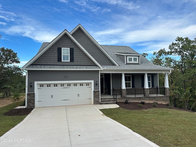 craftsman house with driveway, a garage, a front lawn, a porch, and brick siding