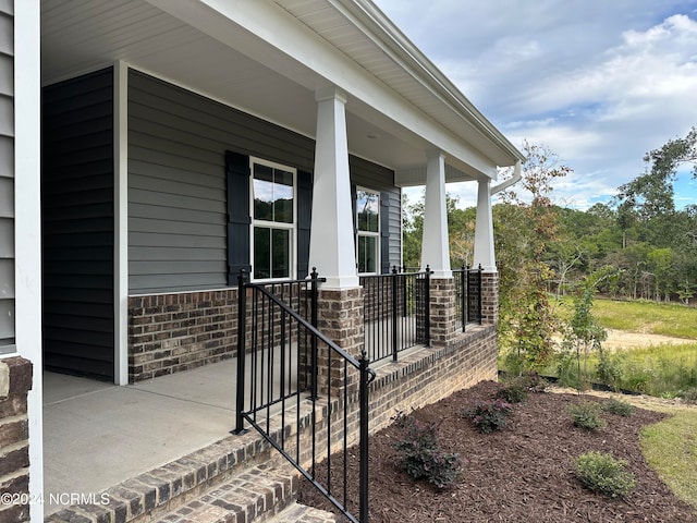 doorway to property with a porch and brick siding