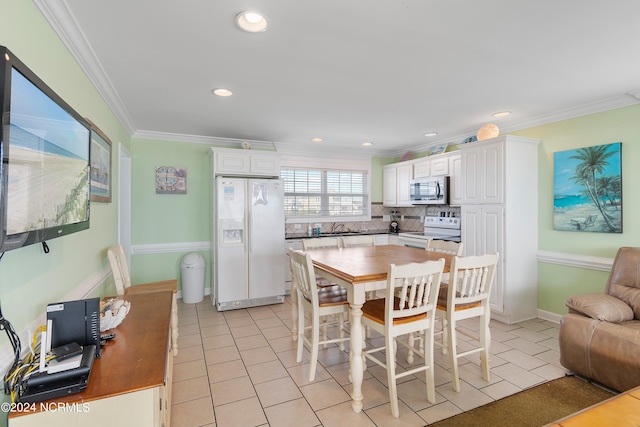 kitchen with white cabinetry, white appliances, light tile patterned floors, and a kitchen bar