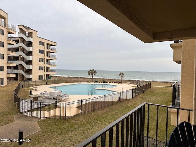 view of swimming pool featuring a water view and a lawn