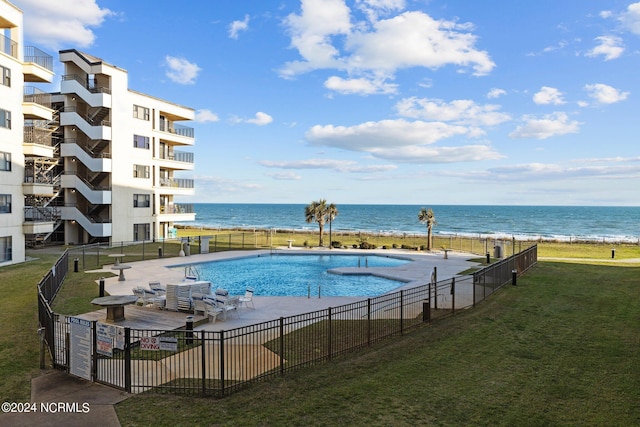 view of swimming pool with a water view and a lawn