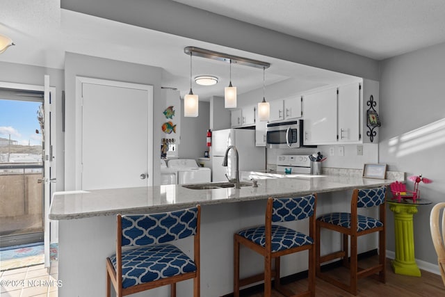 kitchen featuring pendant lighting, white appliances, washer and dryer, and light stone counters