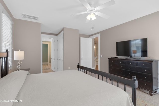 bedroom with light carpet, ceiling fan, and ensuite bathroom