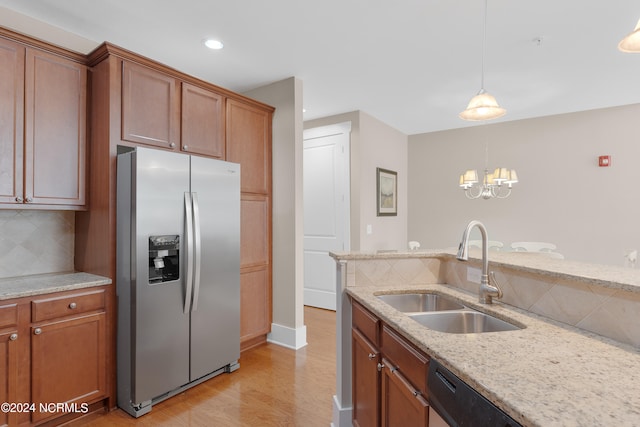 kitchen with tasteful backsplash, light hardwood / wood-style floors, decorative light fixtures, sink, and stainless steel refrigerator with ice dispenser