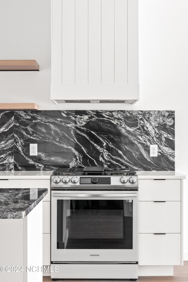 kitchen with white cabinets, wood-type flooring, stainless steel range with gas cooktop, and tasteful backsplash