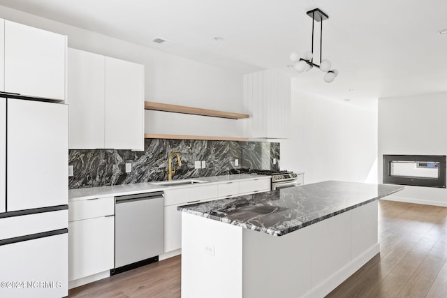 kitchen featuring sink, hanging light fixtures, wood-type flooring, white cabinets, and appliances with stainless steel finishes