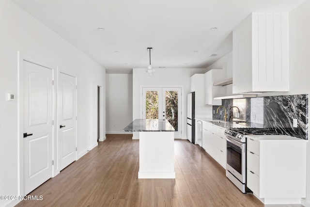 kitchen featuring pendant lighting, a center island, light hardwood / wood-style flooring, fridge, and white cabinetry