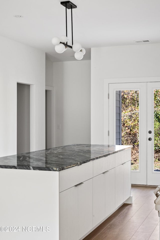 kitchen featuring light wood-type flooring, white cabinetry, and dark stone counters