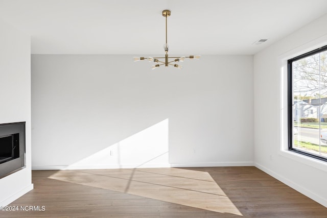 unfurnished dining area featuring hardwood / wood-style floors, an inviting chandelier, and plenty of natural light