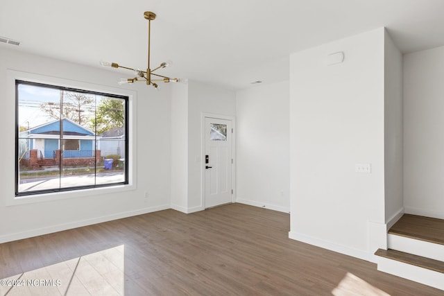 unfurnished living room with hardwood / wood-style floors and a chandelier