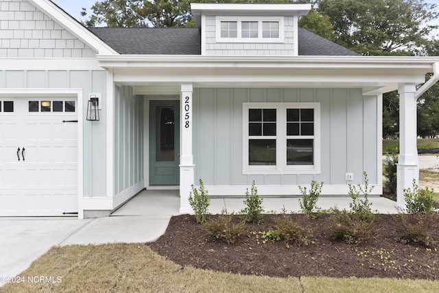 2058 Greenside Manor Dr, Ocean Isle Beach, NC 28469 - property entrance with a porch, board and batten siding, a shingled roof, and a garage