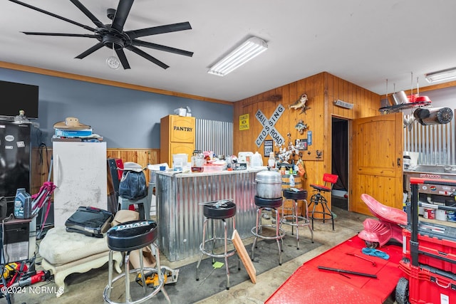 miscellaneous room featuring wood walls, ceiling fan, and concrete flooring