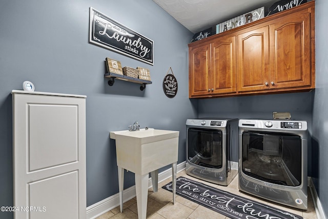 laundry area with washing machine and dryer, light tile floors, and cabinets