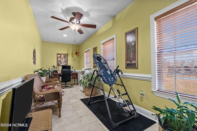 exercise room featuring light tile floors and ceiling fan