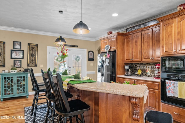 kitchen with decorative light fixtures, light wood-type flooring, black appliances, backsplash, and ornamental molding