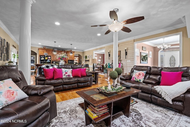 living room with crown molding, ceiling fan with notable chandelier, decorative columns, and light wood-type flooring