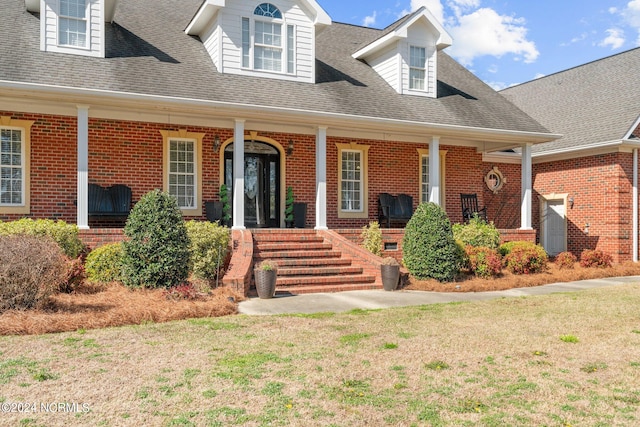 cape cod-style house featuring a front lawn and covered porch